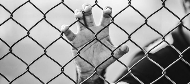 Hand reaching through chain link fence