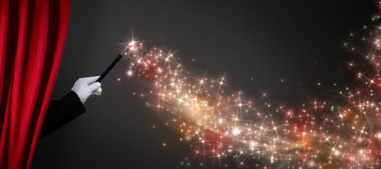 Magician's hand with wand, creating sparkling magic