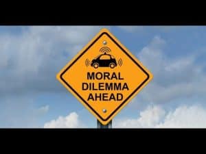 Warning sign: Moral Dilemma Ahead, depicting a self-driving car.