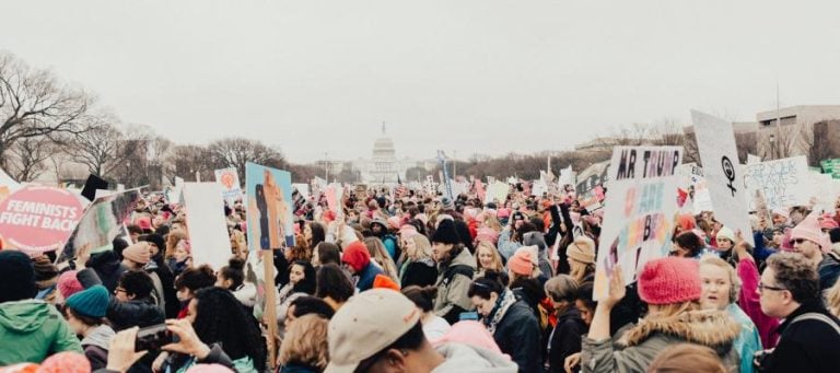 Large crowd of protestors at a political rally, holding signs.