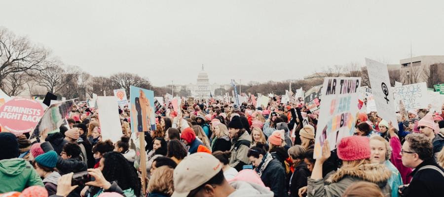 Large crowd of protestors at a political rally, holding signs.