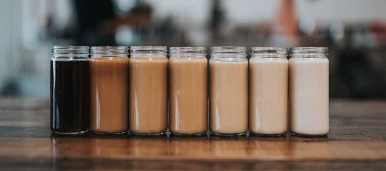 Six glass jars with varying shades of coffee, from dark to light.