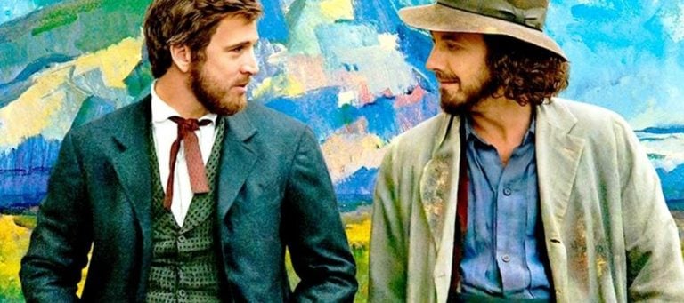 Two men stand side-by-side, against a vibrant Impressionist-style painting.