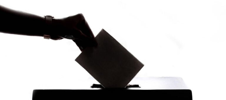 Hand dropping ballot into a box; voting, election, democracy
