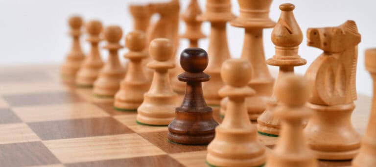 Single dark pawn among light-colored chess pieces on a board. Midlife crisis concept.