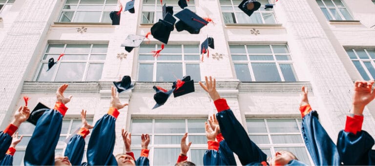 Graduates joyfully toss their caps in the air at graduation.