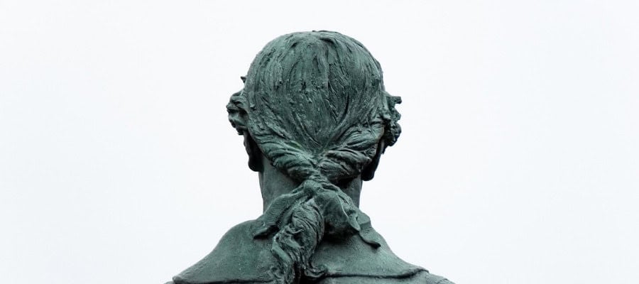 Rear view of a bronze statue, hair styled in a ponytail.