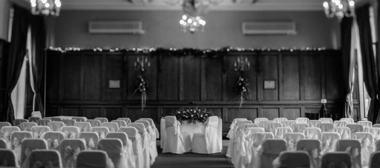 Empty wedding ceremony seating awaits guests in a grand hall.
