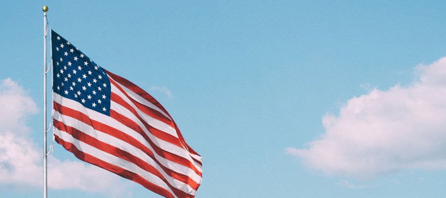 American flag waving in a blue sky with clouds.