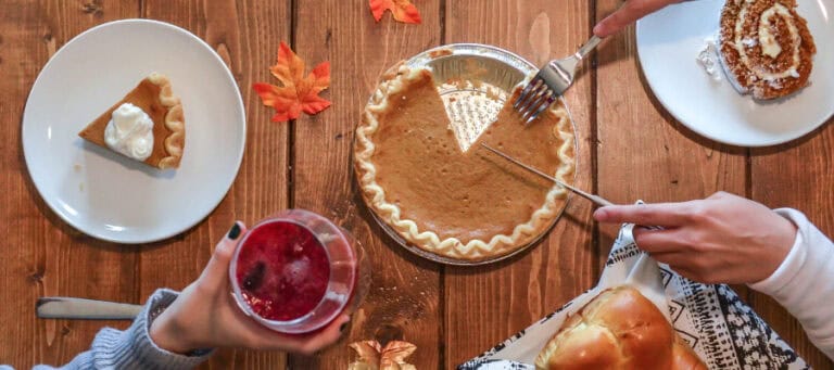 Overhead view of Thanksgiving dinner: pumpkin pie, sweet roll, and drinks.