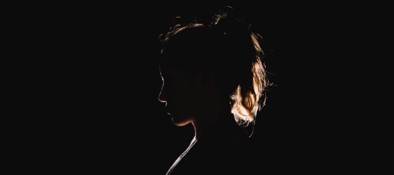 Silhouette of a woman, profile view, hair pulled back.