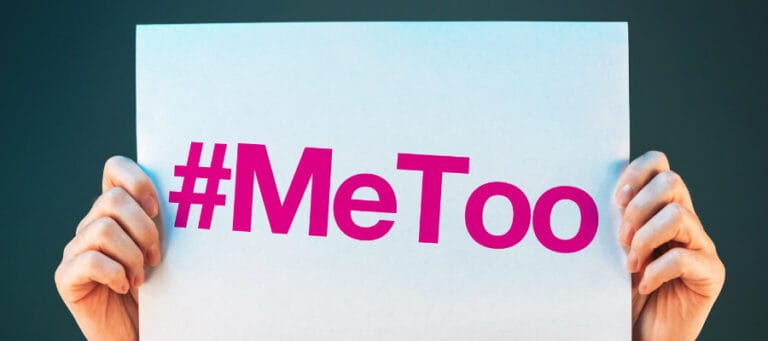 Hands holding a sign reading "#MeToo".