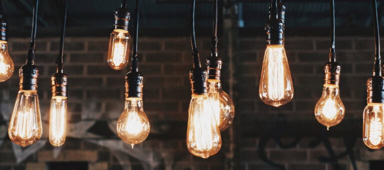 Vintage Edison light bulbs illuminate a dark brick wall. Dark knowledge concept.