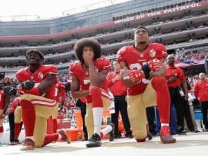 Three NFL players kneel during the national anthem, a powerful display of athlete activism and social commentary.