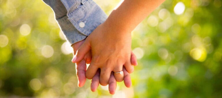 Close-up of two hands clasped together, symbolizing connection and support.