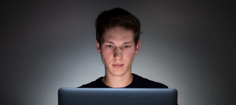 Young man using laptop at night. Is he a criminal?