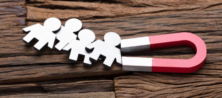 Metal figures representing people being drawn to a magnet.