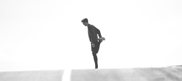 Man stretching leg outdoors, preparing for a run.