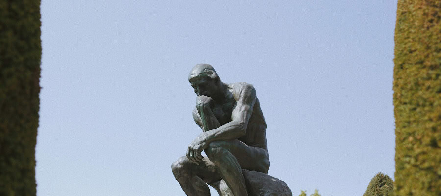 Bronze sculpture of a seated man contemplating, Rodin's "The Thinker.