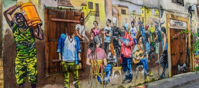 Vibrant street art mural depicting diverse people in a city setting.