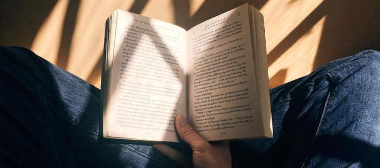 Person reading a book, sunlight illuminating the pages.