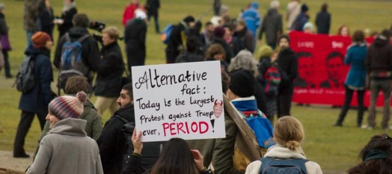 Protestors hold sign: "Alternative fact: Today is the largest protest against Trump ever, PERIOD!