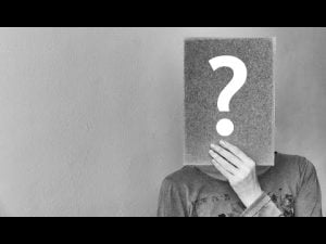 Person holding a sign with a question mark, exploring the concept of self-illusion.