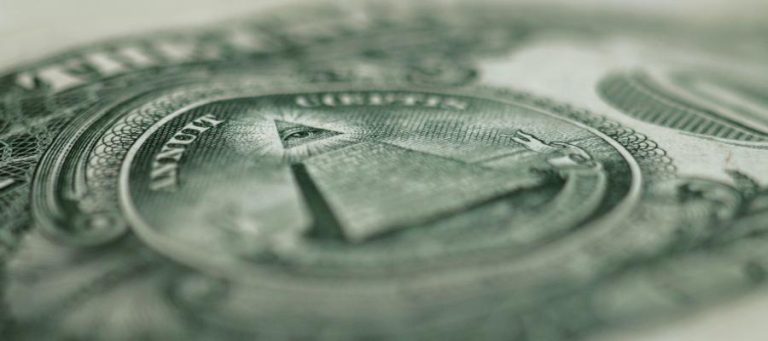 Close-up of the Great Seal of the United States on a dollar bill, featuring the pyramid and eye.