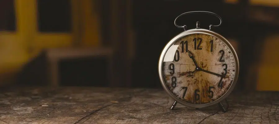 Vintage alarm clock showing the time on a rustic wooden surface.
