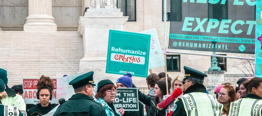 Protestors at a demonstration holding signs with messages about embryos and life.