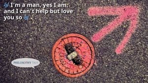 Red utility cover on asphalt with pink markings; lyrics "I'm a man, yes I am, and I can't help but love you so