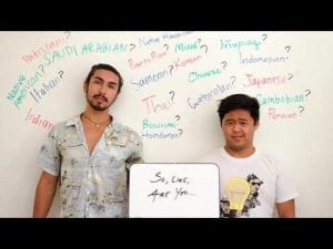 Two young men stand before a whiteboard listing various ethnicities, pondering questions of identity and microaggressions.
