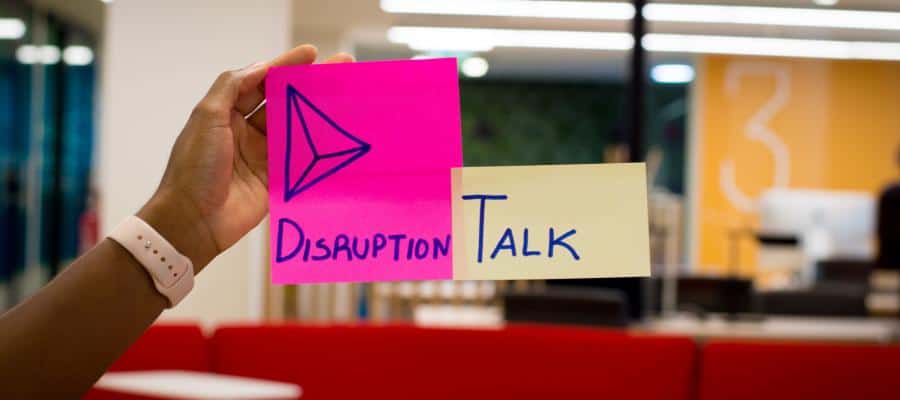 Hand holding sticky notes: "Disruption" and "Talk".