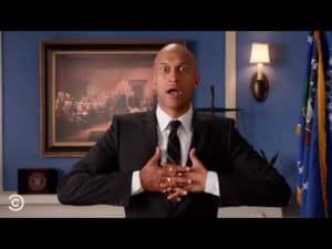 A man in a suit expresses righteous rage, hands clasped to his chest.