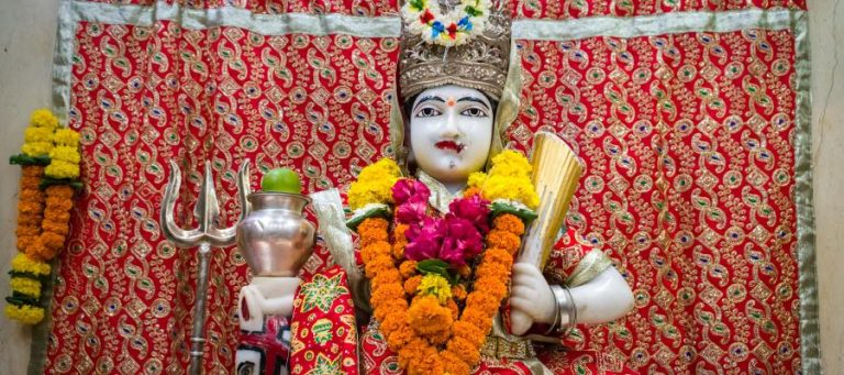 Ornate statue of a Hindu goddess, adorned with flowers and jewelry.