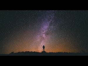 Silhouetted person gazing at a stunning night sky filled with stars and the Milky Way. Awe-inspiring wonder.