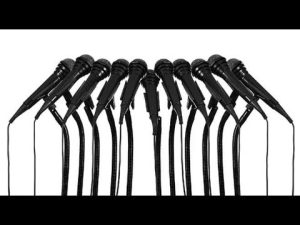 Ten black microphones arranged in a row, symbolizing diverse voices.