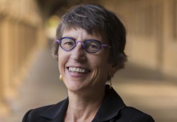 Headshot of smiling woman with short hair and purple glasses.