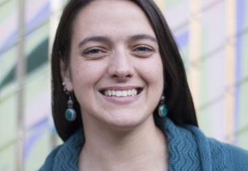 Smiling woman with teal sweater and earrings