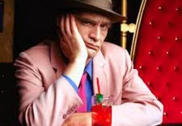 Disappointed man in pink suit sits with a cocktail