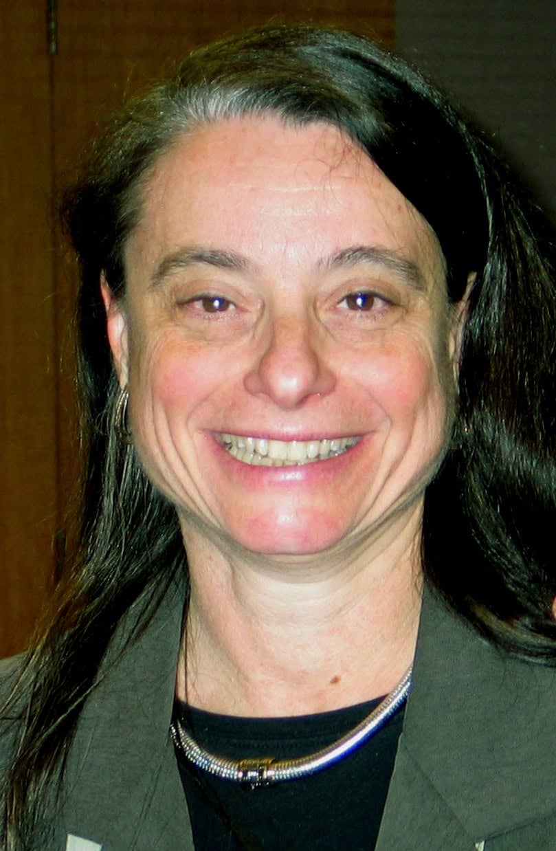 Headshot of a woman with long dark hair, smiling