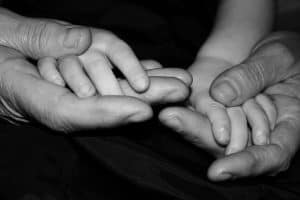Close-up of overlapping hands, showcasing intergenerational connection.
