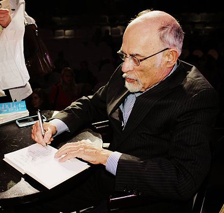 Elderly author signing book, overcoming death's terror.