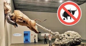 Surreal sculpture of a man riding a bull, defecating a column, with a "No Bull" sign. Truth vs. BS.