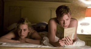 Couple in bed, one reading "Lessing" by Doris Lessing. Summer reading list.