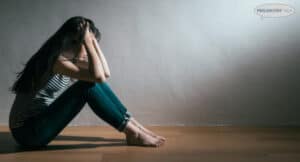 Sad woman sitting on the floor, head in hands. Suicidal ideation.