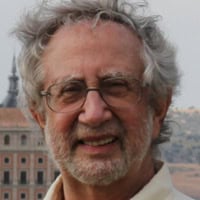 Headshot of a smiling older man with gray hair and glasses