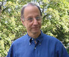 Headshot of a middle-aged man with glasses, wearing a blue shirt.