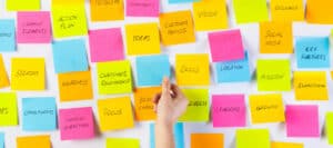 Colorful sticky notes on a whiteboard brainstorm ideas, strategy, and customer relationships. Who owns these ideas?