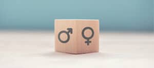 Wooden cube with male and female gender symbols.